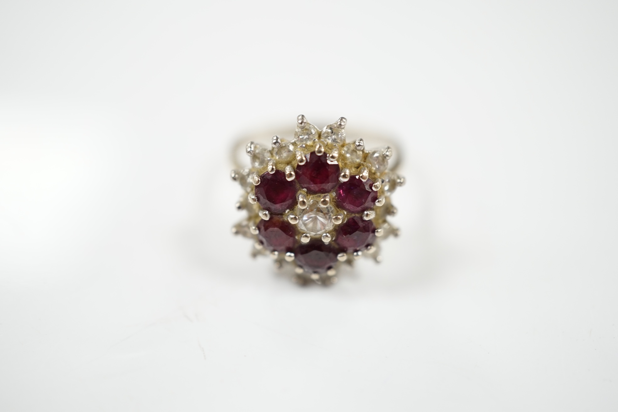 An 18ct white metal, ruby and diamond cluster ring, size P, gross weight 7 grams. Condition - fair